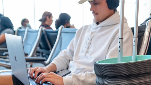 A man typing on your laptop with his Chirp Wheel on the handle of his luggage