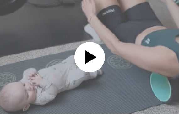 Woman lying beside a baby while using the Chirp wheel on her back